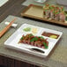 A white porcelain square plate with food on it and a pair of chopsticks.