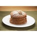 A stack of Krusteaz Buckwheat Pancakes with powdered sugar on a plate.
