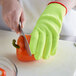 A person wearing yellow Mercer Culinary cut-resistant gloves cutting a bell pepper.