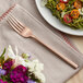 An Acopa Phoenix rose gold stainless steel dinner fork on a plate of food.