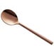 A close-up of an Acopa Phoenix rose gold stainless steel bouillon spoon with a handle.