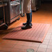 A person standing on a red Cactus Mat in a kitchen.