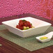 A white square porcelain bowl filled with raw tuna and avocado sits on a table.