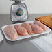 A white foam meat tray of raw chicken meat on a counter.
