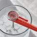 A red AvaTemp pocket probe thermometer in a glass of ice water.