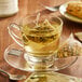 A glass cup of Steep Cafe citrus chamomile tea with a bag of tea on a saucer.