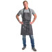 A man wearing a grey Mercer Culinary bib apron with black straps.