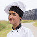 A woman wearing a white Uncommon Chef twill chef's hat.