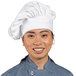 A woman wearing a white Uncommon Chef twill chef hat and smiling.