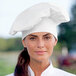 A woman wearing a white Uncommon Chef twill chef hat.