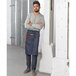 A man wearing a Mercer Culinary indigo denim bistro apron with brown leather details.