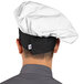 A person wearing a white and black Uncommon Chef poplin chef hat.