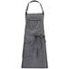A gray apron with black leather accents and ties.