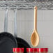 A Vollrath tan high heat nylon spoon hanging from a metal rack.