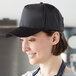 A woman wearing a Henry Segal black 5-panel cap in a professional kitchen.