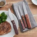 A plate of steak and broccoli with a Choice jumbo steak knife with a wooden handle.
