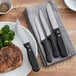 A plate of steak and broccoli with a Choice stainless steel steak knife with a black polypropylene handle.