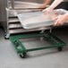 A hand holding a tray over a Chicago Metallic steel sheet pan dolly.