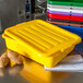 A yellow Carlisle polypropylene lid on a yellow plastic container with potatoes.
