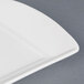 A close-up of a CAC Paris French bone white china fashion platter with a curved edge.