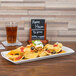 A CAC Paris china fashion platter of nachos with sour cream and cheese on a table with a beer and a glass of beer.