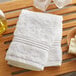 A Lavex Luxury white washcloth on a wooden surface with soap.