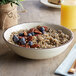 A Carlisle Mingle sweet cream melamine bowl filled with oatmeal topped with blueberries and pecans.