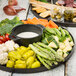 A Tablecraft brown melamine platter of vegetables and dip with a jar of green olives.
