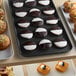 A black Cambro market tray filled with cookies and muffins on a bakery display counter.