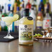 A bottle of Agalima Organic Margarita Mix on a bar counter with a drink.
