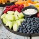 A Tablecraft Lunara brown melamine platter with fruit and dip on a wood surface.