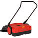 A red and black Bissell Commercial manual power sweeper with a handle.