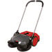 A red and black Bissell Commercial Deluxe Turbo manual power sweeper with wheels.