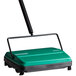 A green and black Bissell Commercial floor sweeper with a handle.