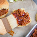 A close up of a BBQ pulled pork sandwich with AAK Grill Blazin' BBQ Sauce.