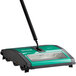 A Bissell Commercial green and black floor sweeper with a handle.