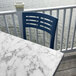 A white Grosfillex marble table top on an outdoor patio with a chair and water in the background.