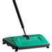 A green and black Bissell Commercial floor sweeper.