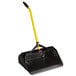 A black and yellow Rubbermaid plastic upright dustpan with a yellow handle.