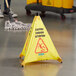 A yellow triangular Carlisle wet floor sign with black "Caution" text on it.