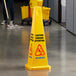 A yellow Carlisle wet floor caution cone with black text on the floor.