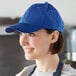A woman wearing a blue Mercer Culinary baseball cap in a professional kitchen.