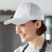 A woman wearing a white Mercer Culinary 6-panel baseball cap.