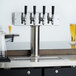 An Assure 4-tap beer tower on a counter with two glasses of beer.