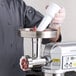 An Avantco MIX8 mixer being used to grind meat with an Avantco meat grinder attachment.