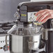 A hand pouring oil into an Avantco MIX8 Series mixer with a bowl guard.