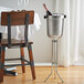 An American Metalcraft champagne bucket stand with a champagne bottle in a bucket on a table.