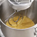 An Avantco mixer with a flat beater mixing yellow liquid in a bowl.