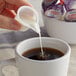 A person pouring Nestle Coffee-Mate Italian Sweet Creme into a cup of coffee.