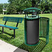 A green Ex-Cell Kaiser Streetscape outdoor trash receptacle with canopy and door next to a green park bench.